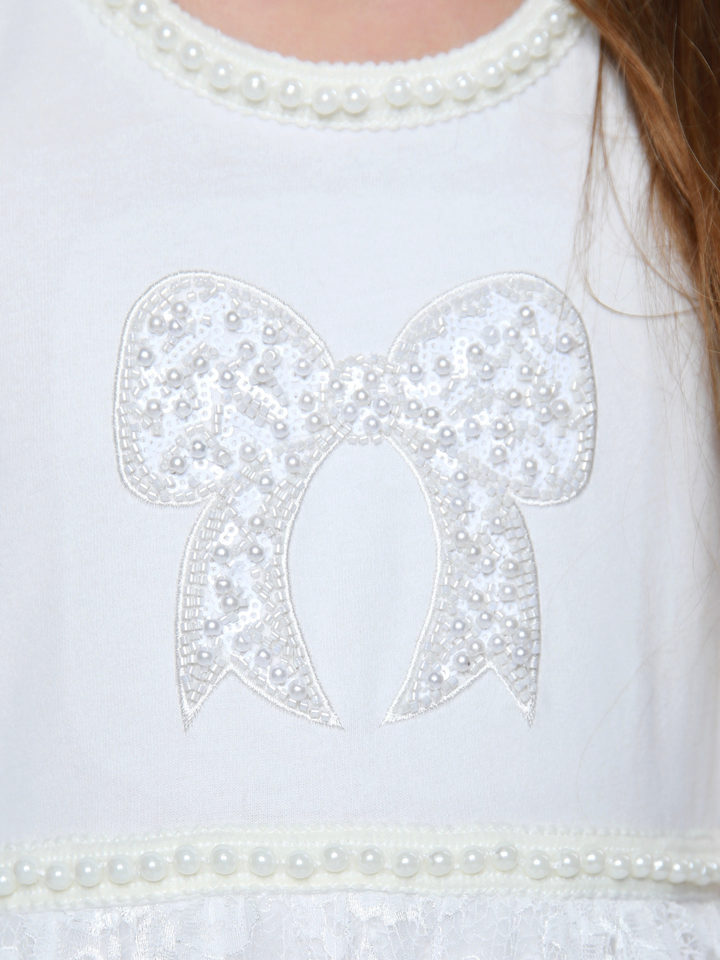 Close up of pearl trim neckline and bow on girls ivory dress
