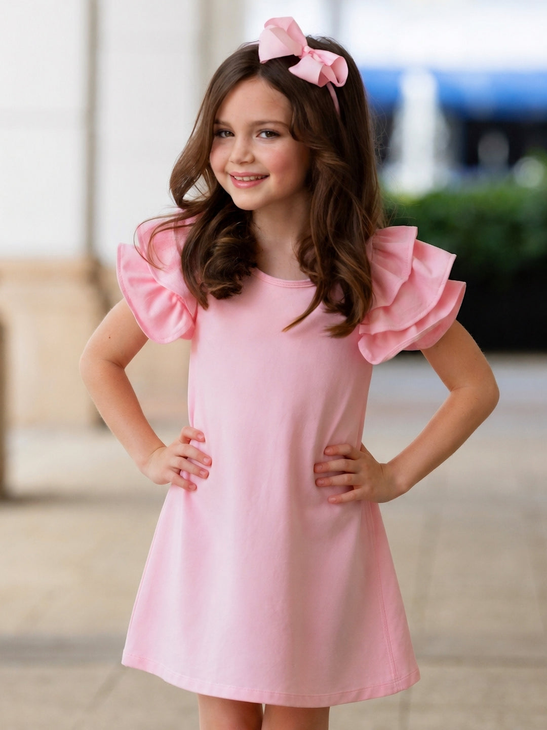 Girl wearing a pink ruffle sleeve swing dress.