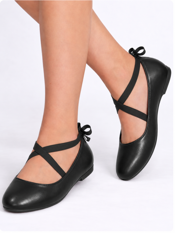 Girl wearing black ballet flats with crisscross straps and bow details