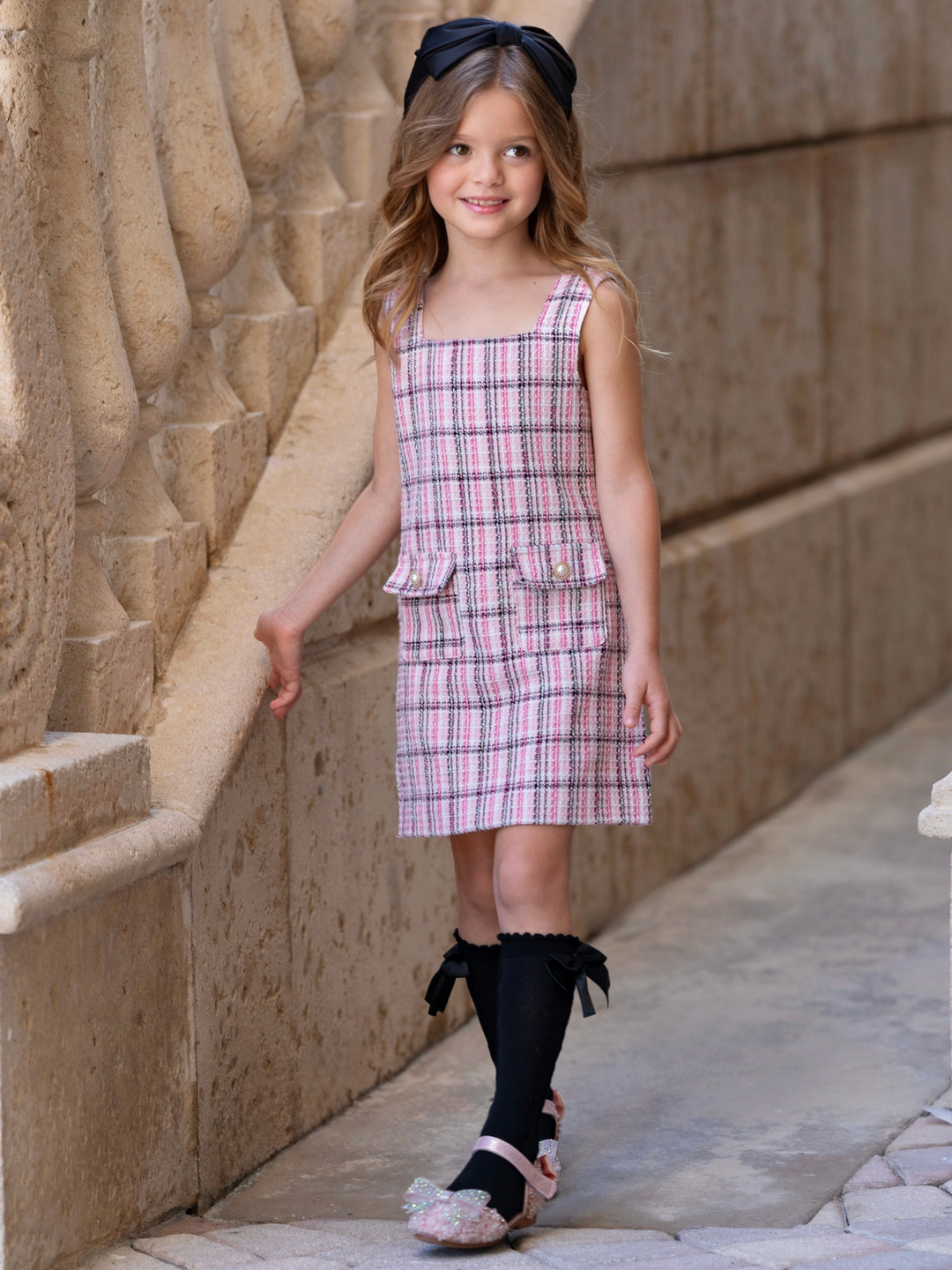 Girls pink tweed dress featuring textured tweed fabric and decorative pocket accents.