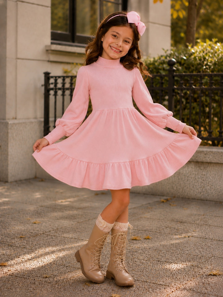 Girl wearing a blush ribbed long sleeve twirl dress with ruffle hem and boots.