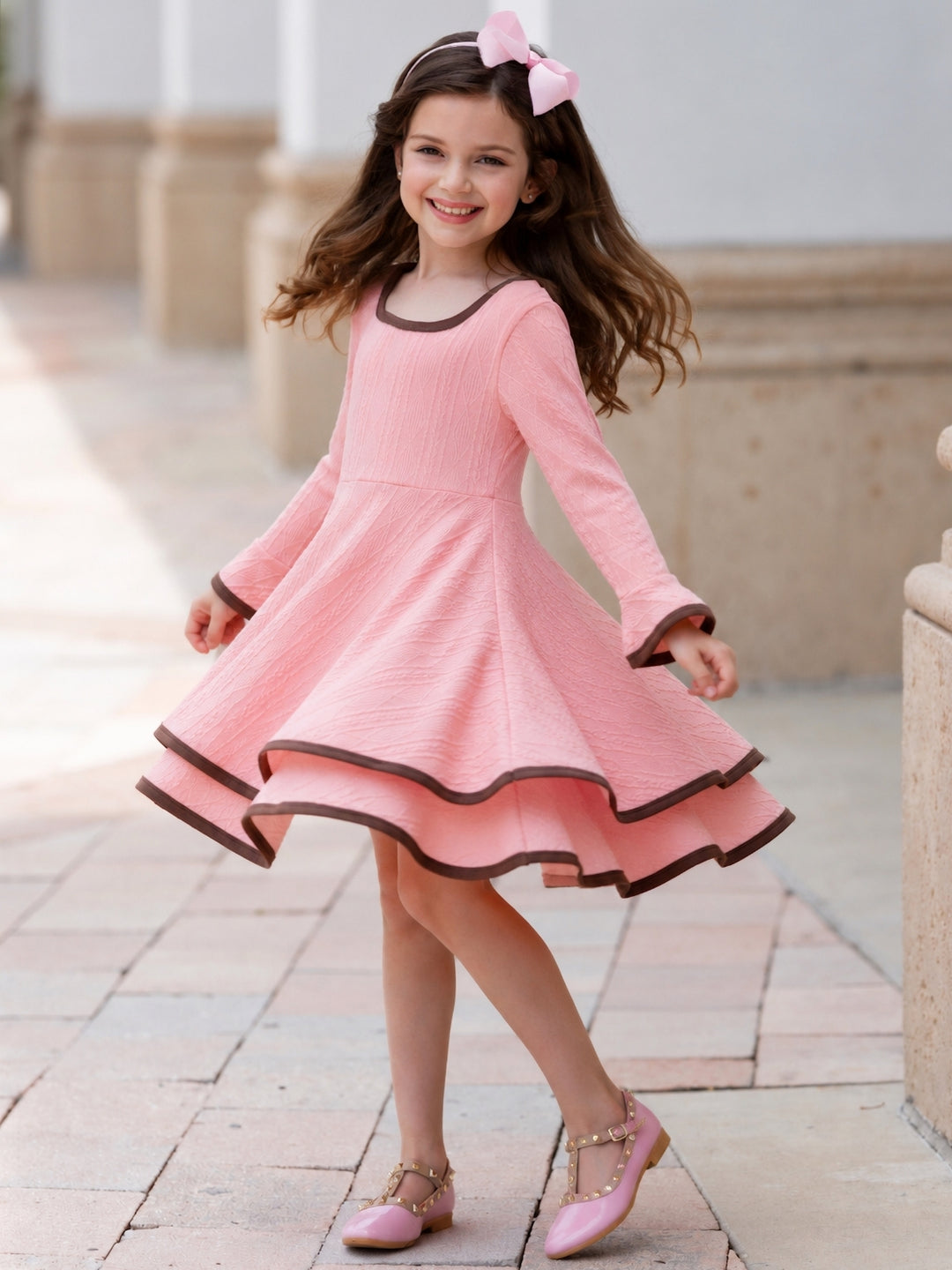 Girl wearing a blush textured knit dress with brown contrast trim.