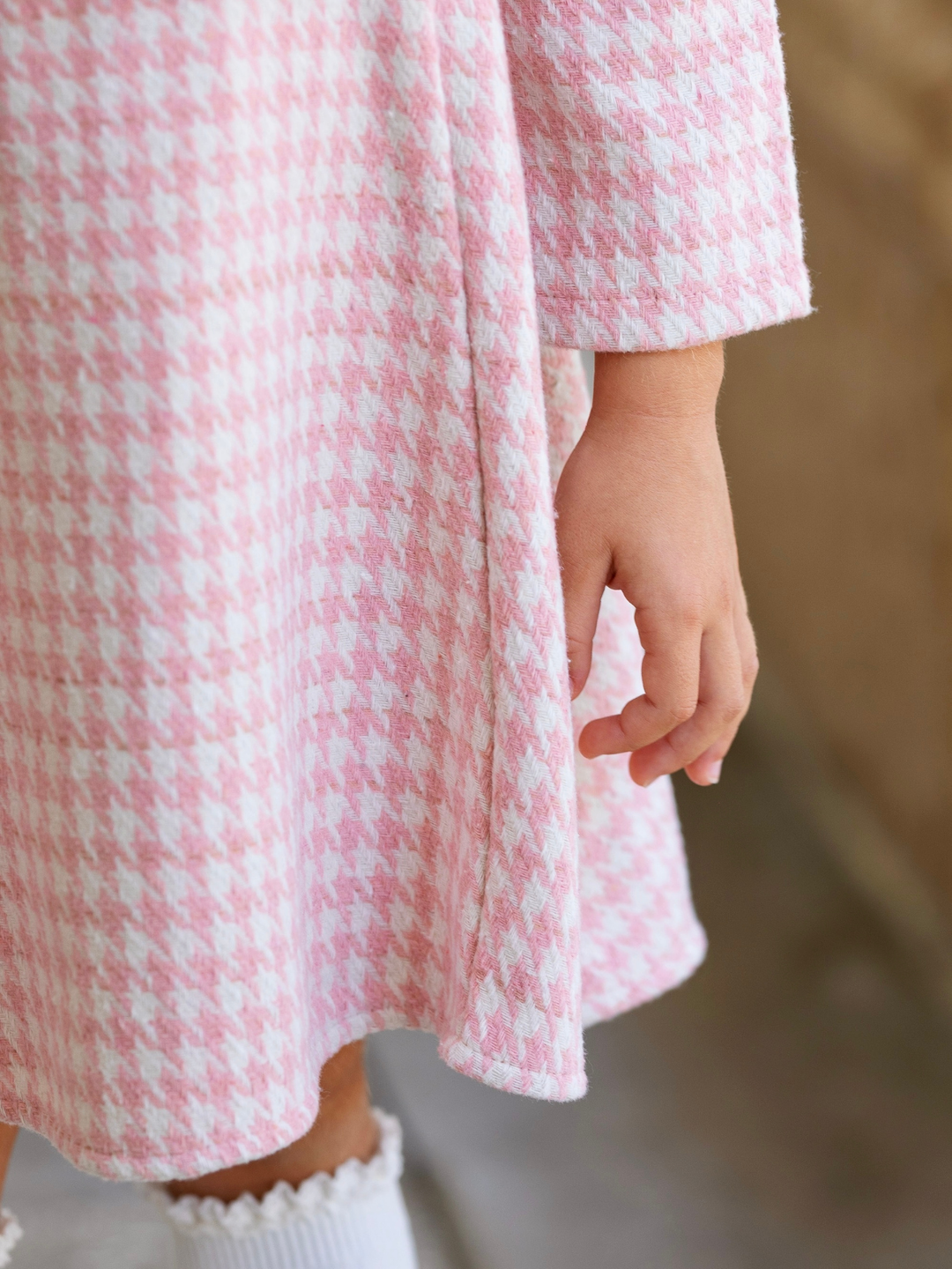 Close up of a pink and ivory houndstooth dress.