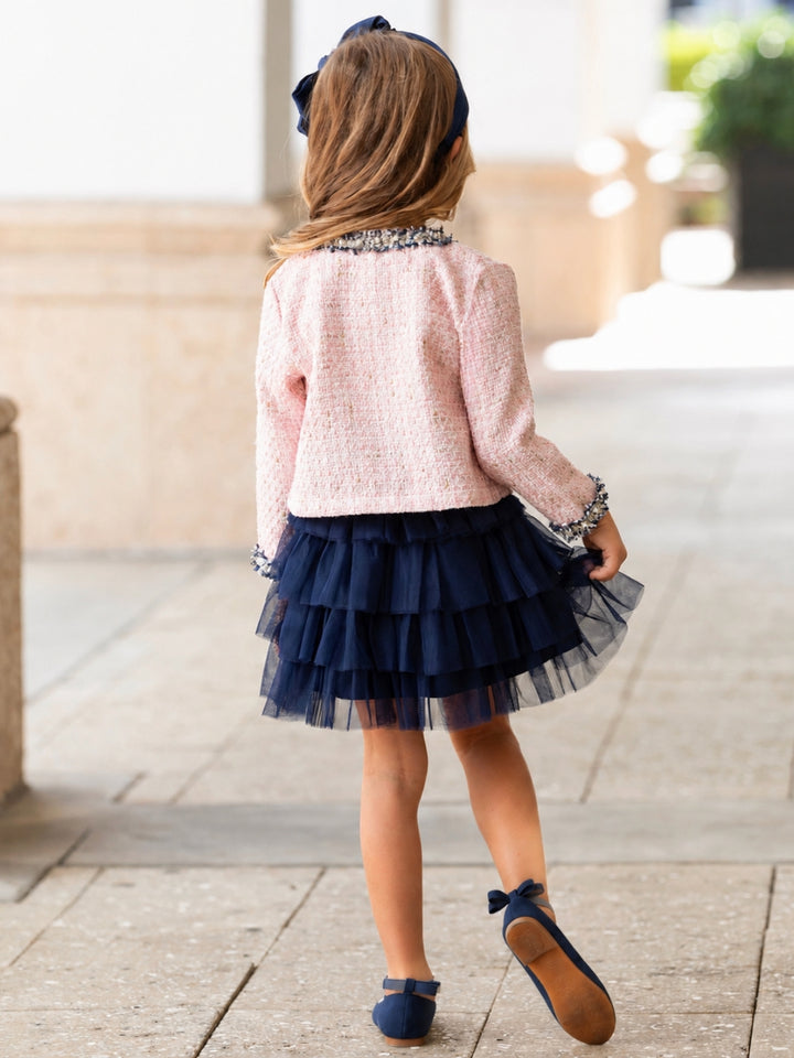 Girl wearing a blush tweed jacket and a navy layered tulle skirt for special occasions.