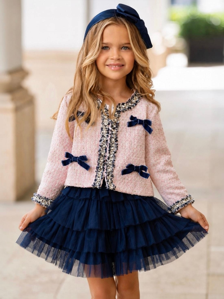 Girl wearing a blush tweed jacket with velvet bows and a navy layered tulle skirt for fall and holiday occasions.