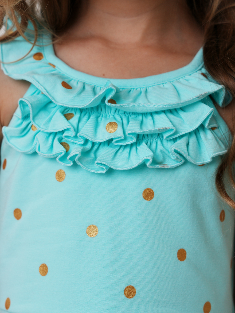 Little girl in blue summer dress with gold polka dots and ruffle details