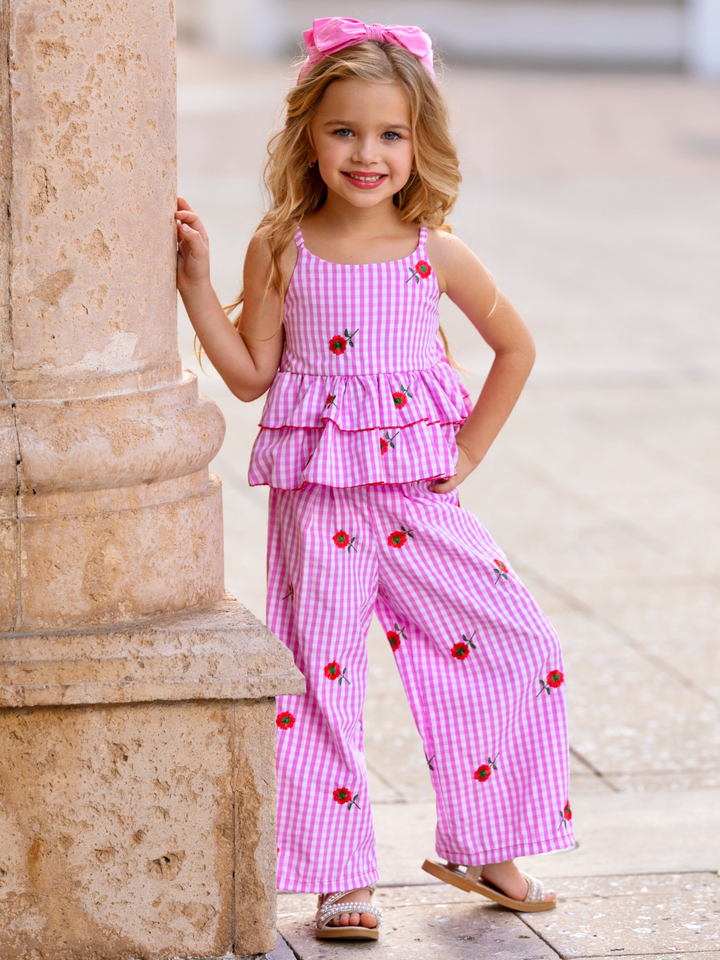 Girl wearing a pink gingham embroidered peplum top and wide-leg pants from the spring collection by Mia Belle Girls
