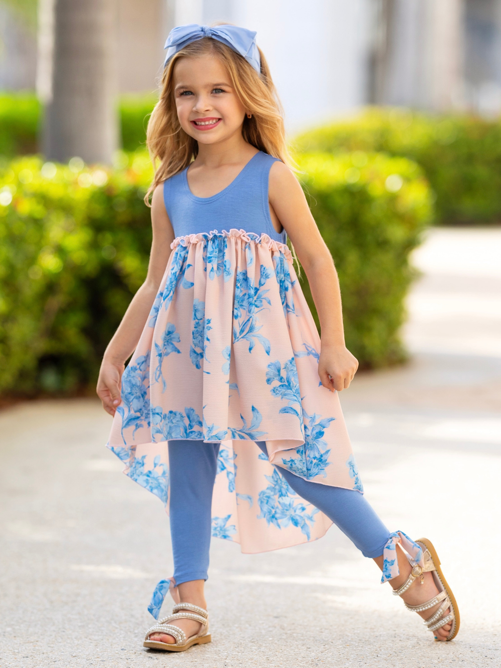 Girl wearing a blue floral high-low tunic and legging set from the spring collection by Mia Belle Girls