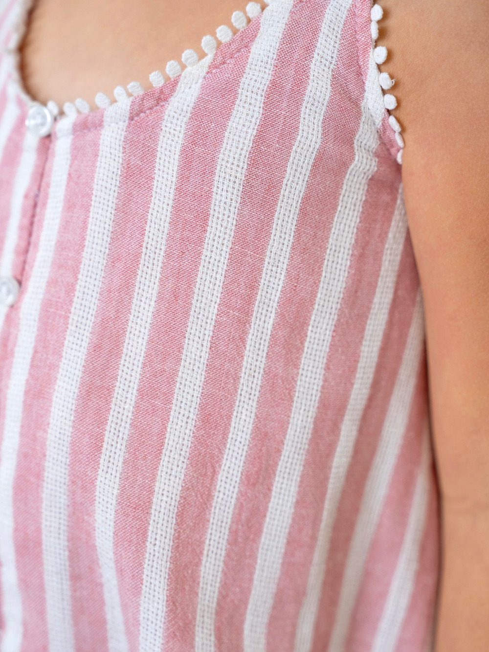 Close up of pink and white stripe fabric with pom trim
