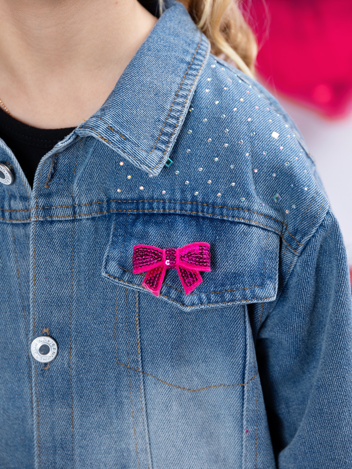 Close up of large pink sequin bow on girls denim jacket