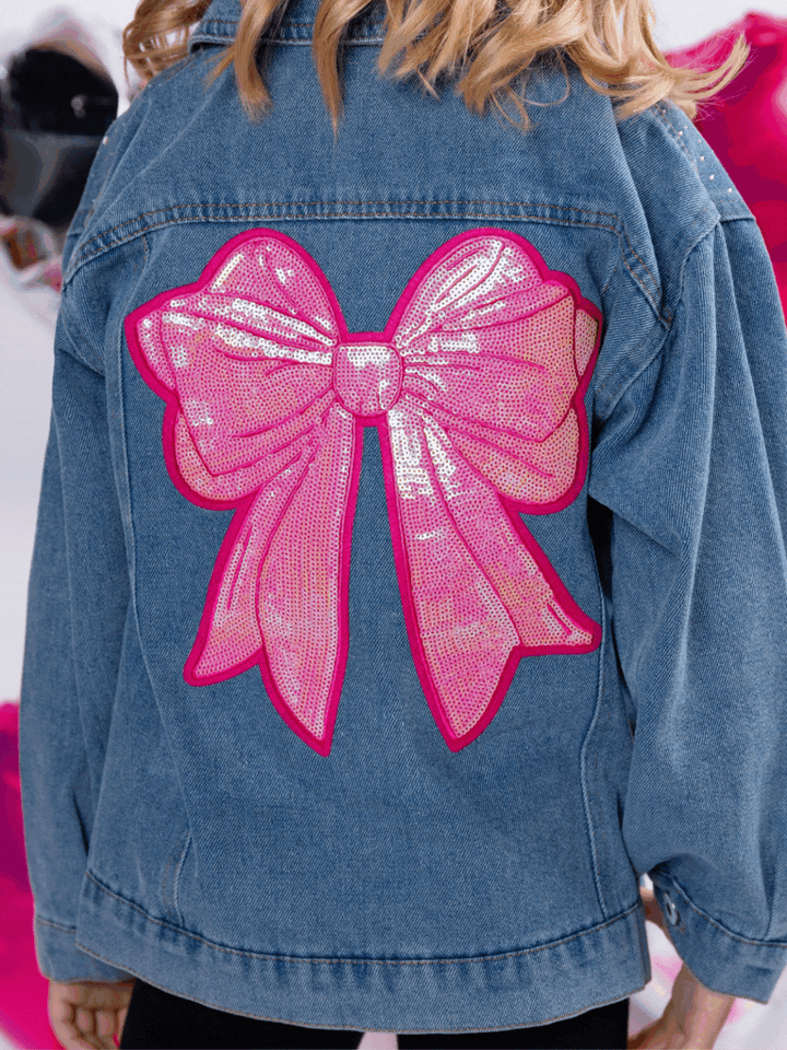Girl wearing denim jacket with large pink sequin bow on the back