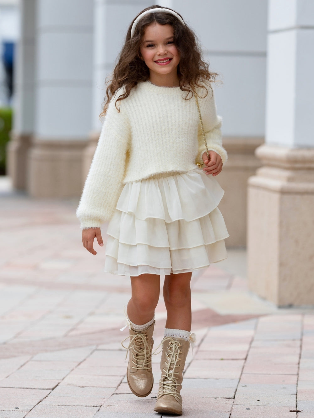 Girl wearing an ivory cozy sweater with a layered tiered skirt.