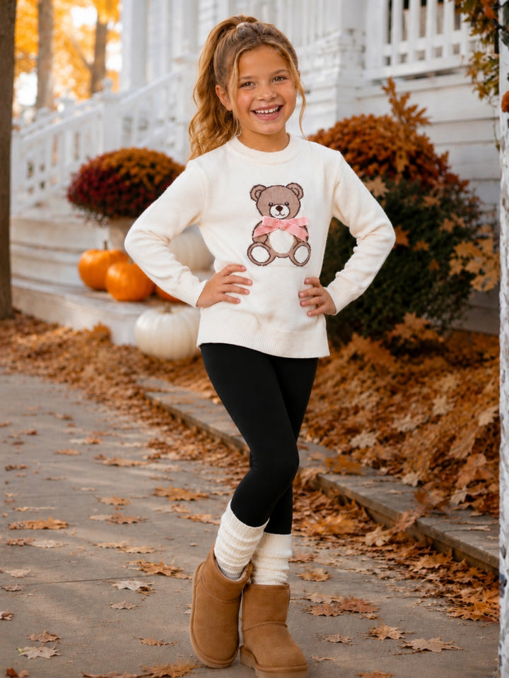 Girls cozy knit sweater with teddy bear graphic and pink bow.